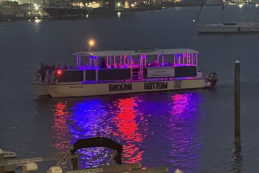 Un bote llamado 'Bikini Bottom' con luces de colores reflejándose en el agua. 1