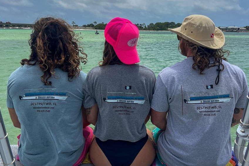 Tres personas en un bote usando camisetas a juego con información del destino. 3