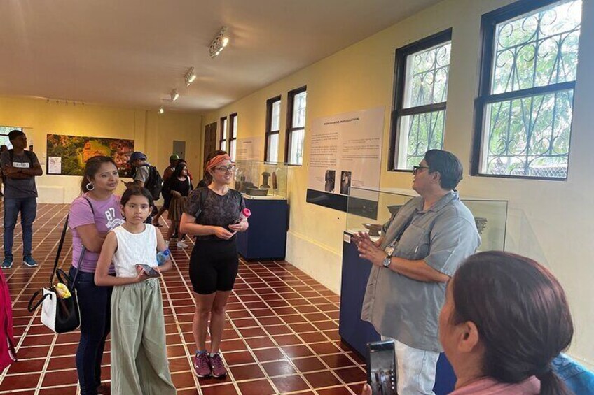 A group of people in a museum-like setting with informational displays and a tiled floor. 5