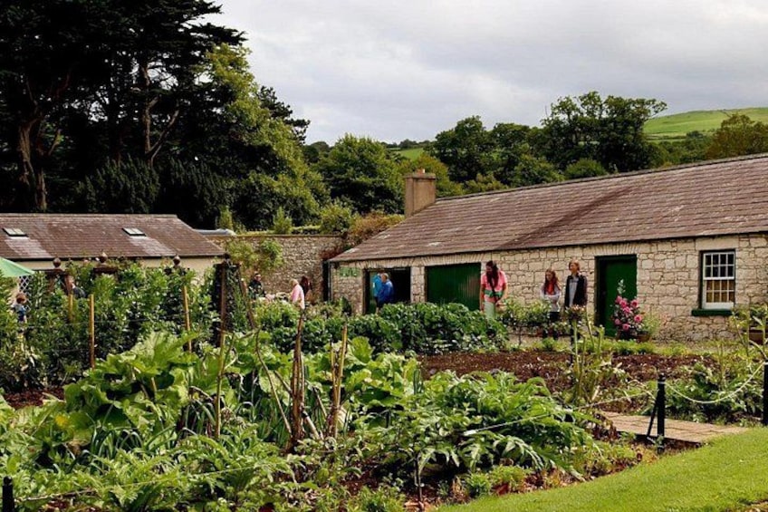 A stone building with green doors, surrounded by lush gardens and trees. 4