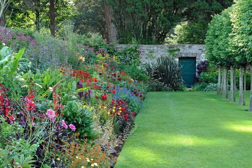 A lush garden with a variety of colorful flowers, a well-maintained lawn, and a stone wall. 3