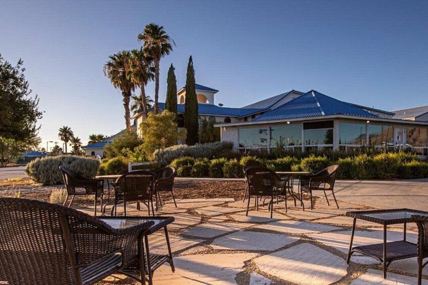 An outdoor seating area with wicker chairs and tables, a building with a blue roof, and palm trees. 3