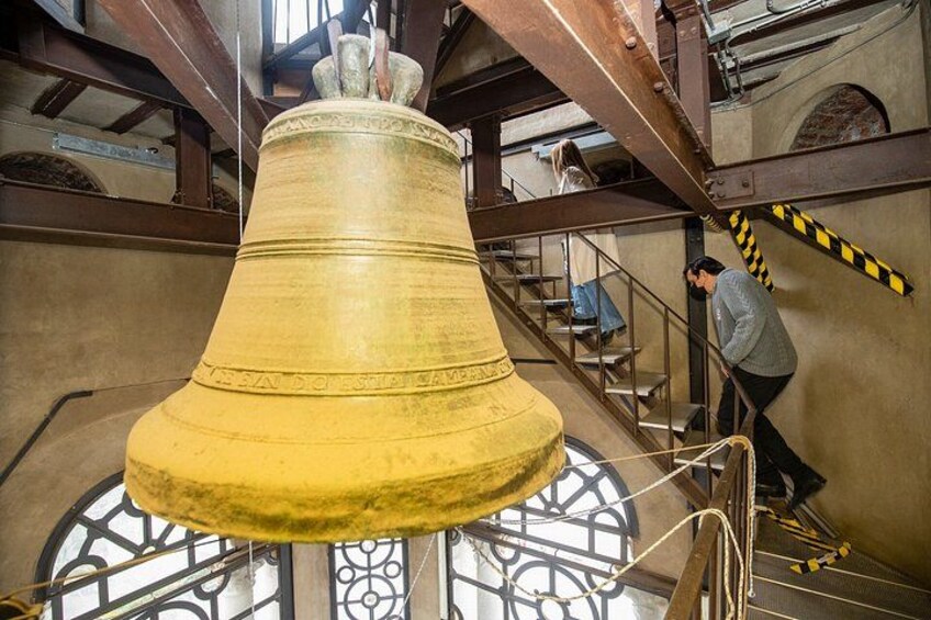 A large bell suspended from a metal structure with a staircase leading to a platform. 3