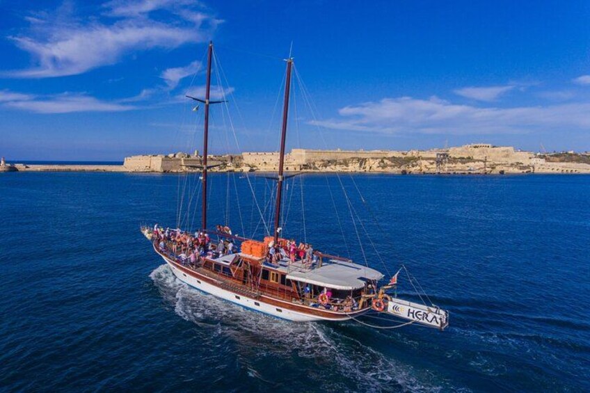 A traditional sailing boat with multiple masts and passengers, sailing on a calm sea with a coastal town in the background. 5