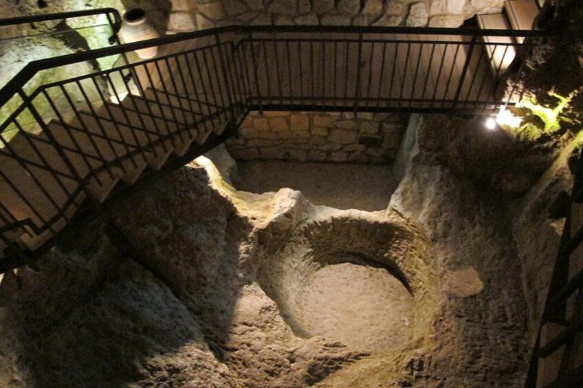 Un pozzo in pietra con ringhiera metallica, circondato da mura di pietra. 2