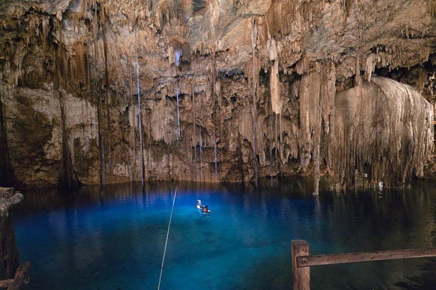Una cueva con estalactitas y una persona descendiendo en rappel a un estanque de agua. 5