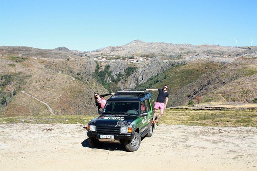 A vehicle parked on a dirt road with a hilly landscape in the background. 3