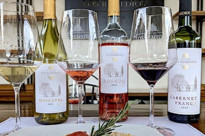 A table with wine glasses and bottles, including labels like 'Los Remedios' and 'Rosado 2021'. 5