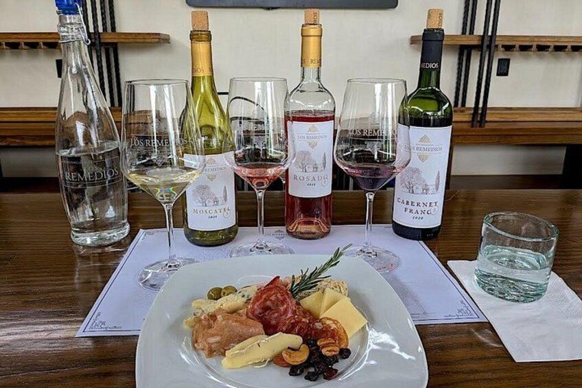A table with a plate of food and several wine bottles and glasses. 1