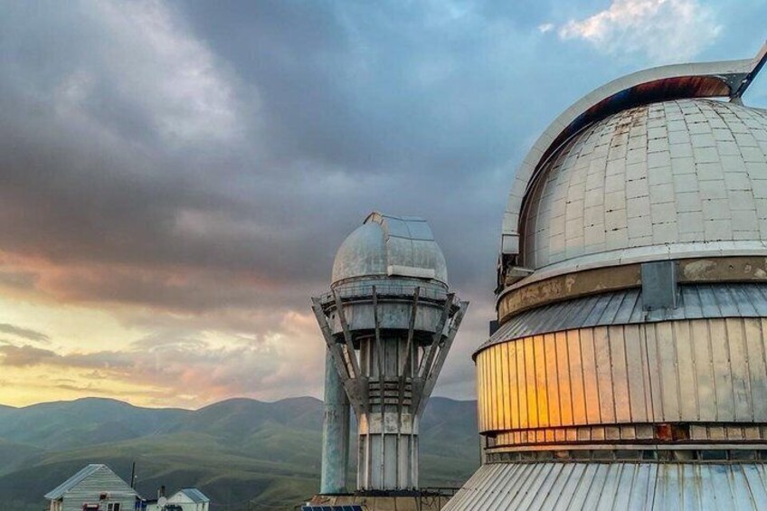 A large observatory with a prominent dome and a tall tower against a mountainous backdrop. 1