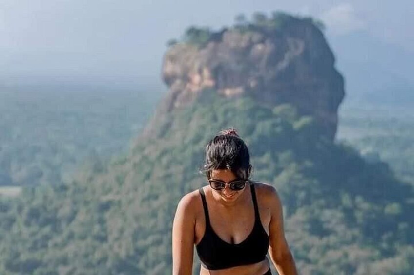A person in a black sports bra and shorts, standing with a mountainous landscape in the background. 2