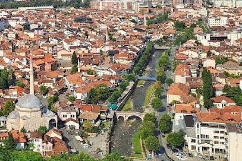 A densely packed urban area with a prominent river running through it, surrounded by buildings with red-tiled roofs. 1