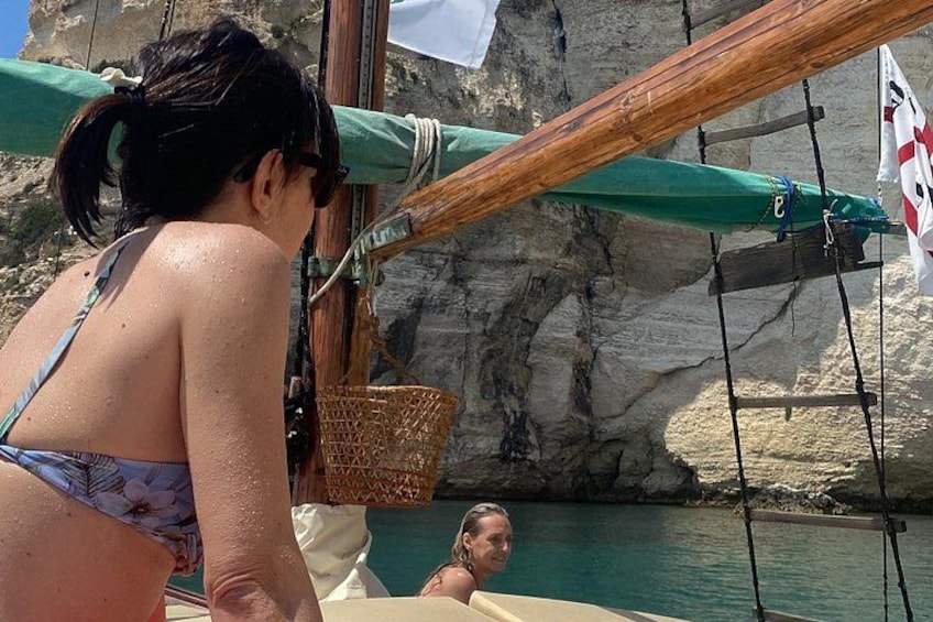 A person in a bikini on a boat, a rocky shoreline, and a flag. 1