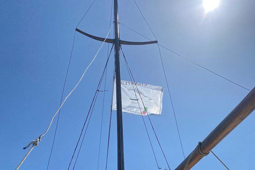 A flag on a mast with a clear blue sky and a sun in the background. 5