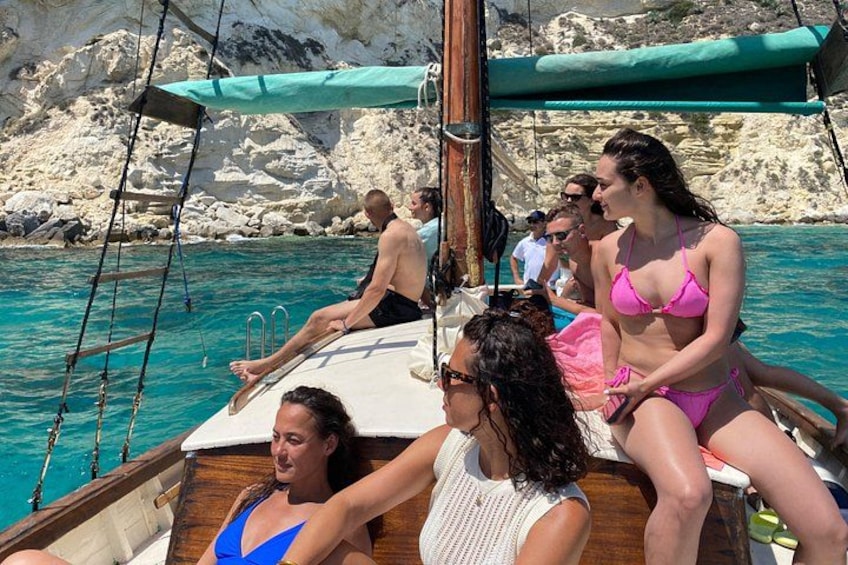 People on a boat with rocky cliffs and clear blue water in the background. 3