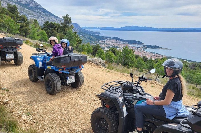 Trois quads sur un chemin de terre, avec une vue panoramique sur un lac et des montagnes en arrière-plan. 2