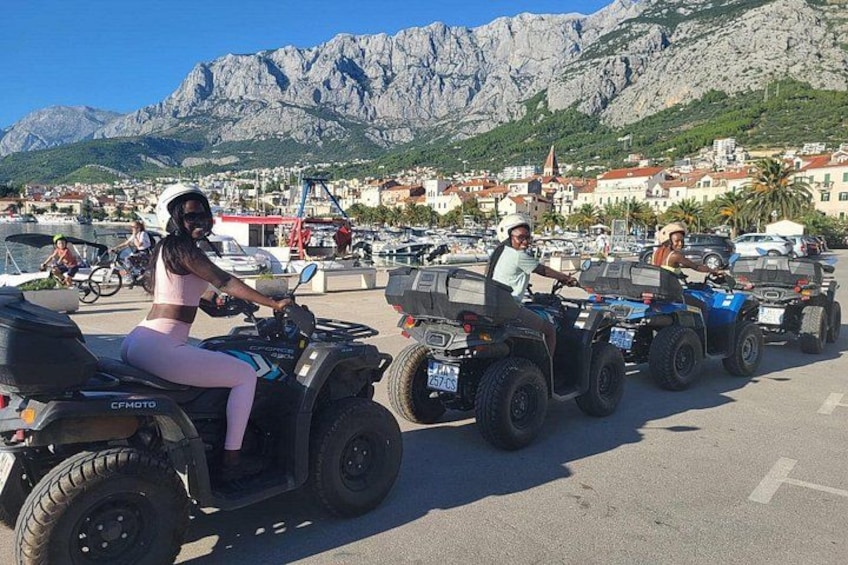 Un groupe de personnes conduisant des quads sur un parking, avec des montagnes en arrière-plan. 4
