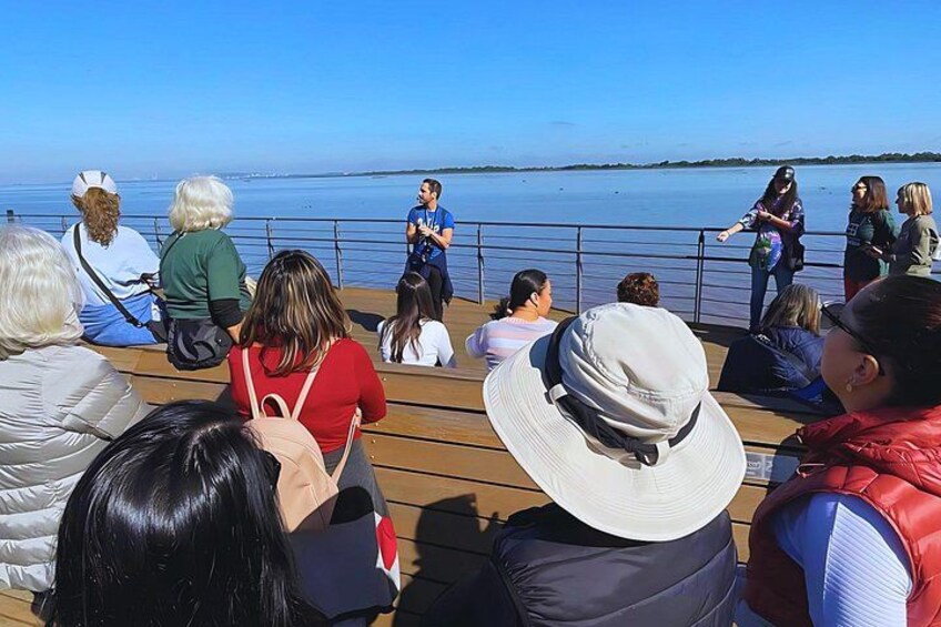 Un grupo de personas en un muelle de madera con vista a un cuerpo de agua. 1