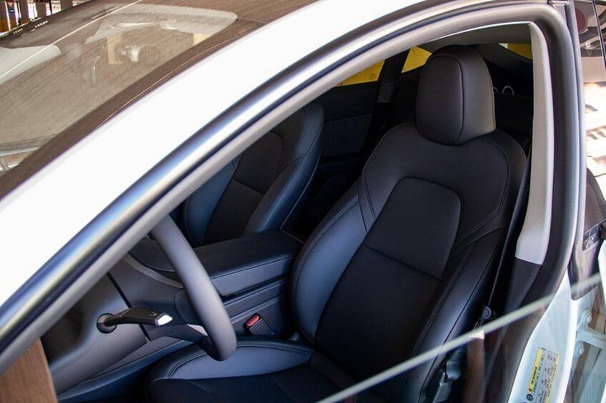 A car's interior with black seats and a steering wheel. 3