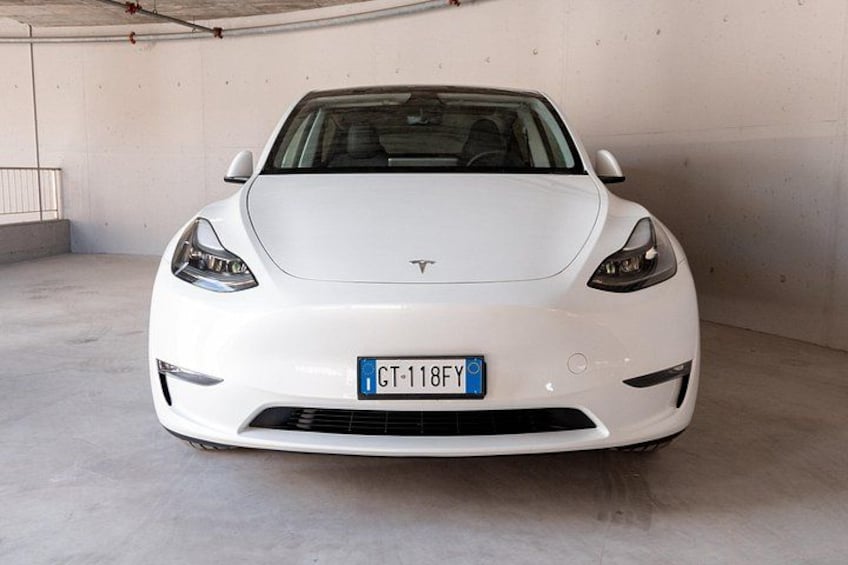 A white Tesla Model 3 parked in a garage. 2