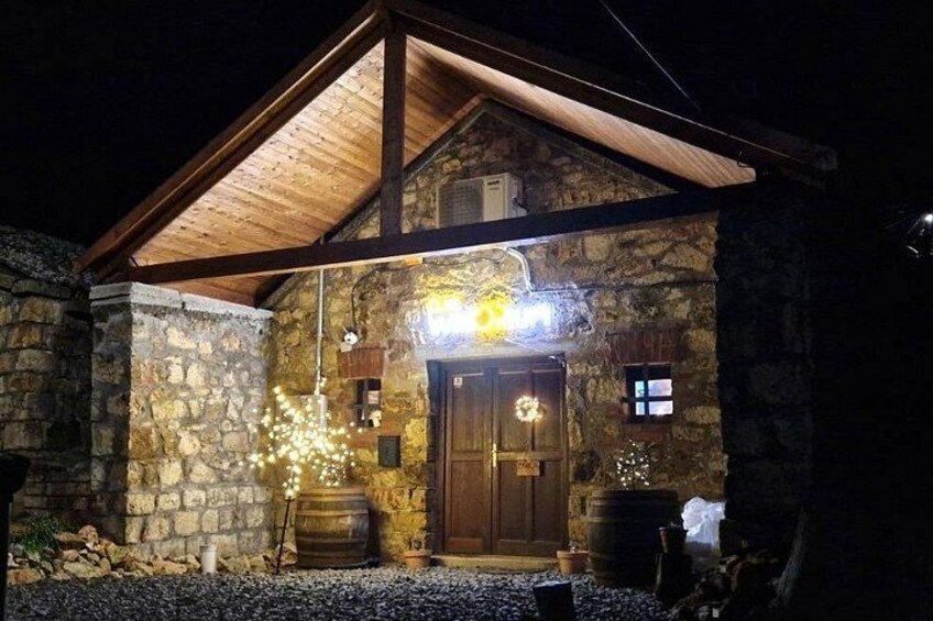 A stone building with a wooden roof, a wooden door, and a porch with string lights. 4