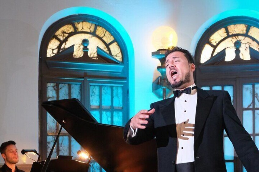 A man in a tuxedo singing into a microphone. 1
