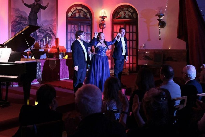 A formal event with a piano, a woman in a blue dress, and a man in a suit on stage. 3