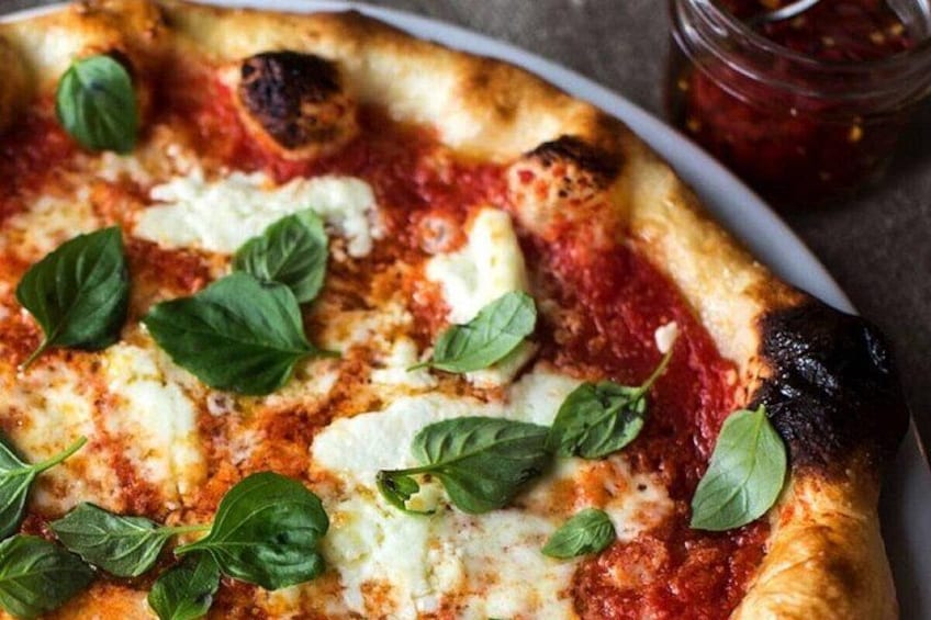 A pizza with tomato sauce, cheese, and basil leaves. 2
