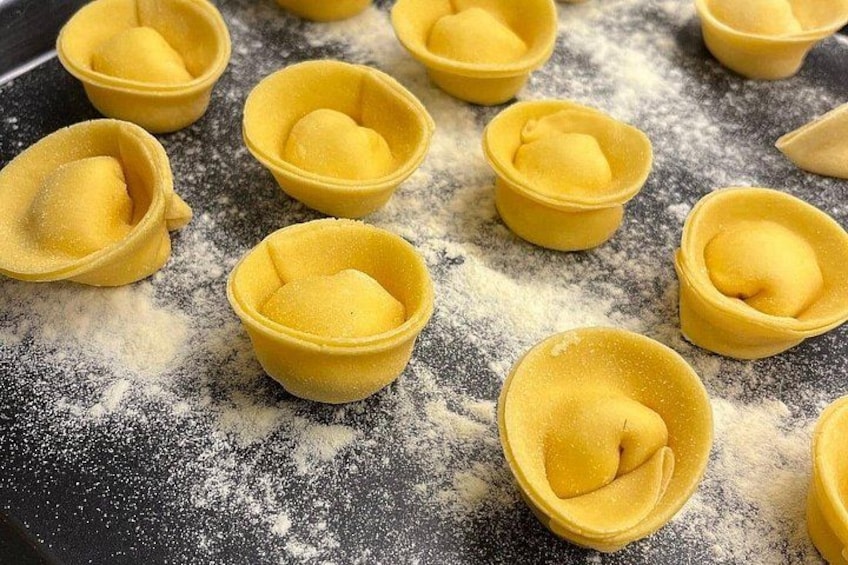 Petites pâtes en forme de coquillage, de couleur jaune, disposées sur une surface farinée. 2