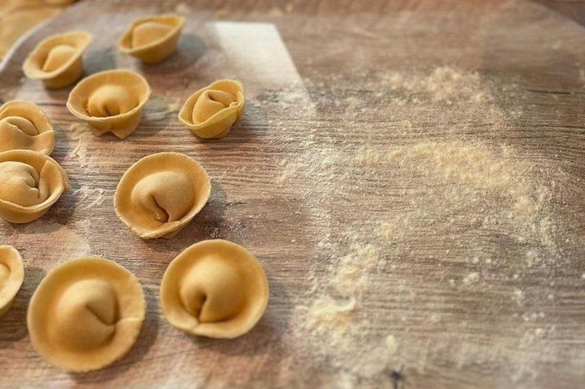 Des pâtes crues en forme de coquillages, disposées sur une surface en bois, avec de la farine éparpillée autour. 3