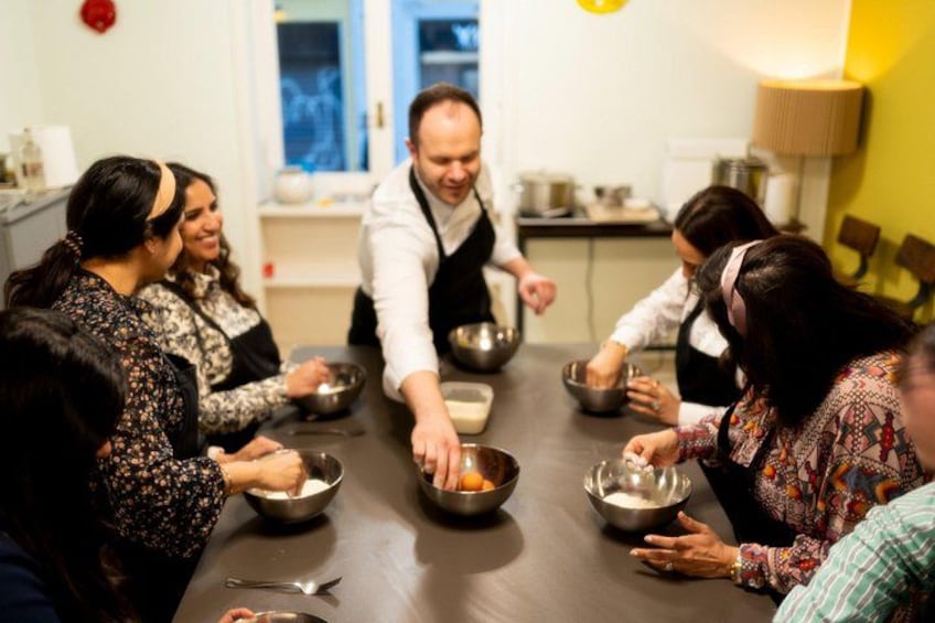 Un groupe de personnes est réuni autour d’une table. Certaines d’entre elles tiennent des bols. La pièce est éclairée par une lampe et possède une fenêtre. 5