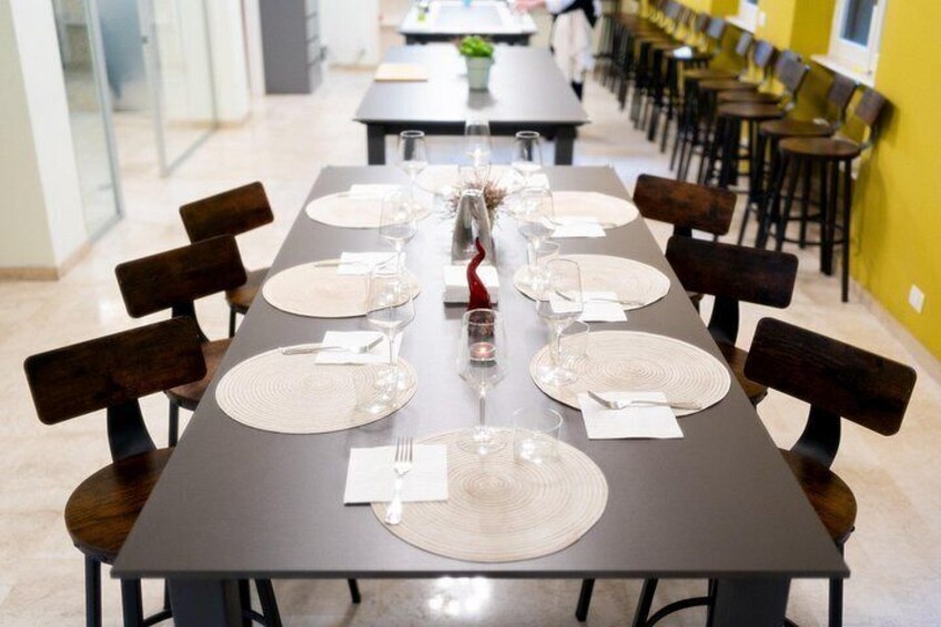 Een lange eettafel, gedekt met borden, glazen en bestek, omringd door stoelen. 4