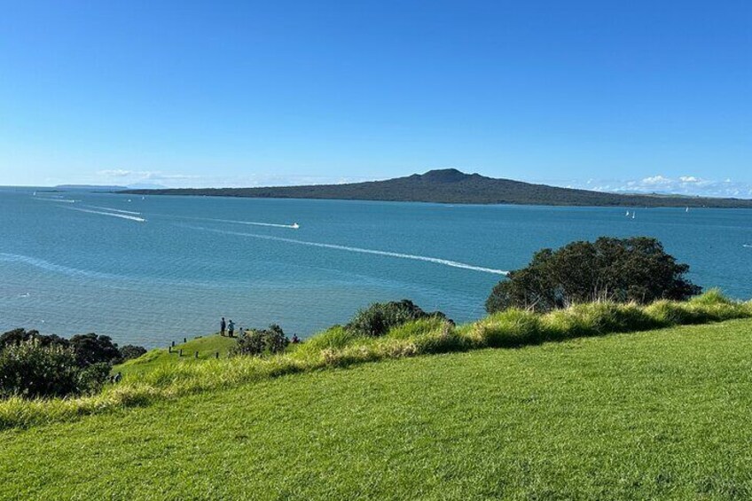 A coastal landscape with a grassy foreground, a body of water, and a distant mountain. 4