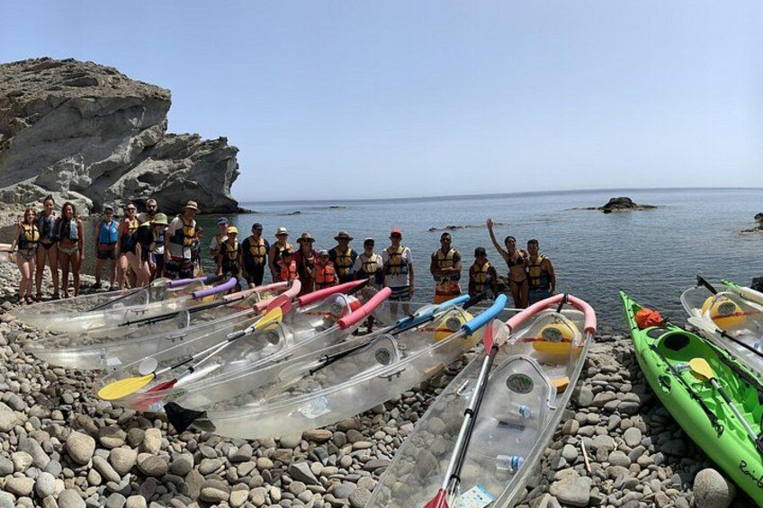 Un groupe de personnes se tient sur une plage rocheuse, et des kayaks sont alignés à proximité. 5