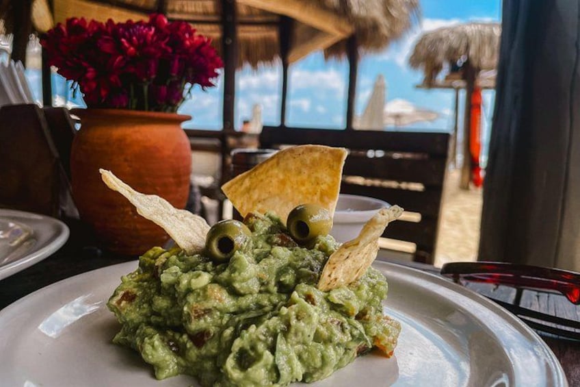 A plate of guacamole with tortilla chips and olives. 2