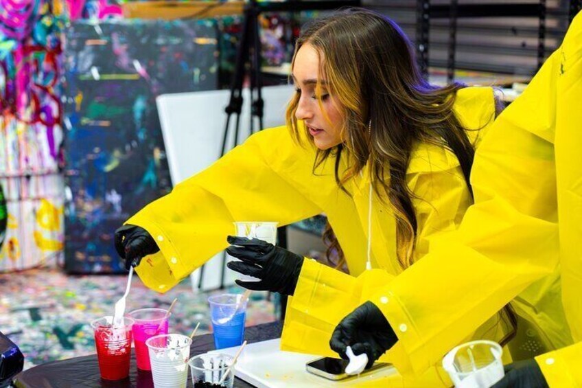 Una persona con impermeable amarillo pintando con un pincel sobre un lienzo. 5