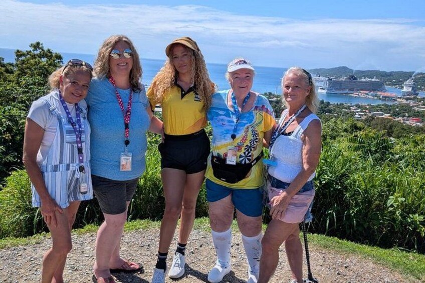 A group of people standing on a hill with a view of a coastal city and greenery in the background. 2