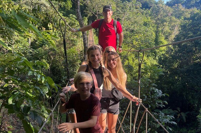 En gruppe mennesker på en hængebro i en skov. 2