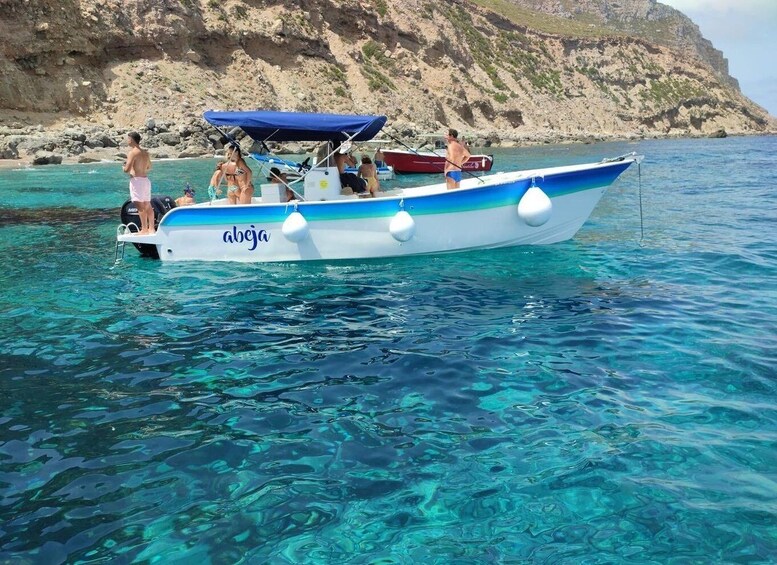 A boat named 'abeja' on clear turquoise water with rocky cliffs in the background. 2
