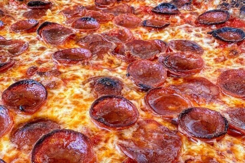 En närbild på en pepperoni-pizza med smält ost och skivor av pepperoni. 1