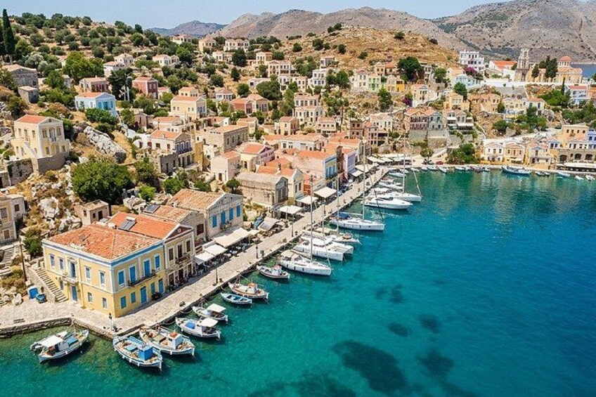 A coastal town with buildings along the waterfront, boats docked in the harbor, and hills in the background. 5