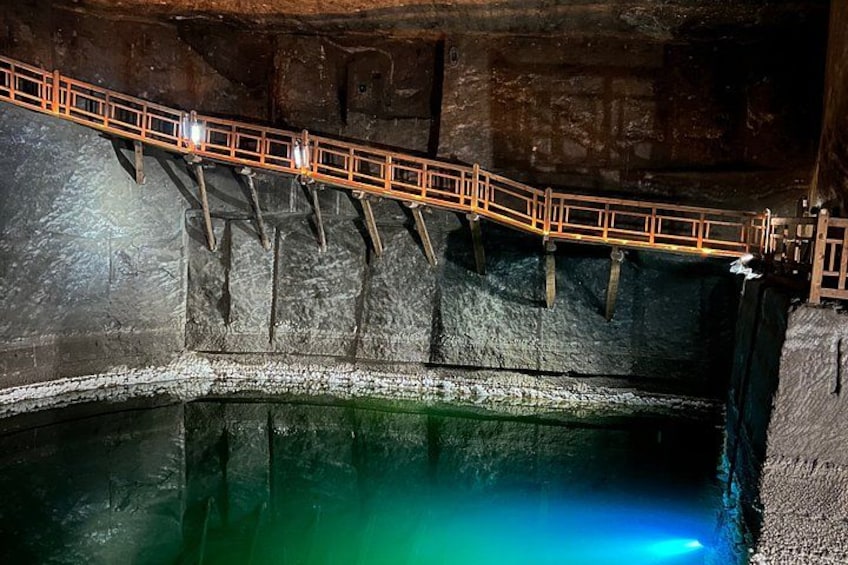 Una grotta con una passerella di legno che scavalca una pozza d'acqua. 3