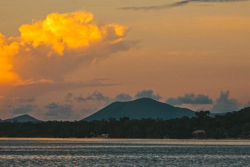A sunset over a body of water with a mountain in the background. 3