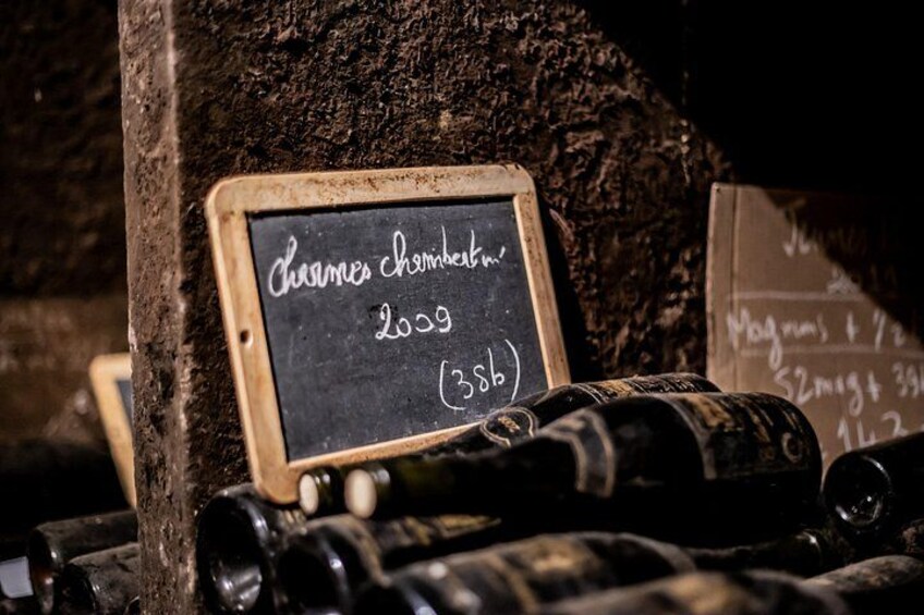 A wine cellar with a chalkboard displaying 'Charmes chateau 2009 (3386)'. 3