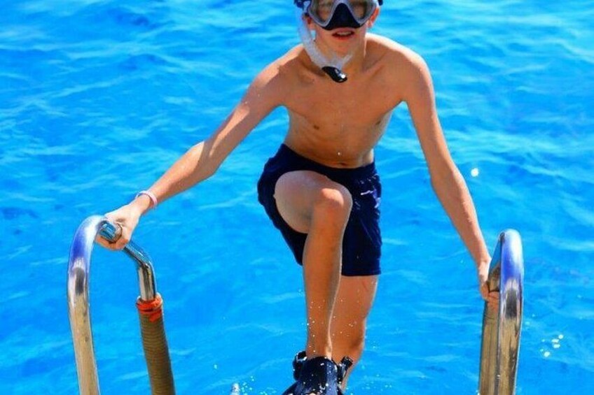 A person in swim trunks and goggles standing on a pool ladder. 4
