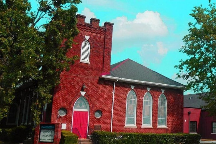 En rød murstenskirke med et kirketårn, buede vinduer og en rødlakeret dør. 2