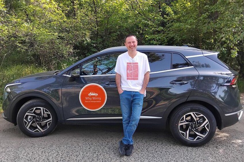 A person standing next to a dark-colored SUV with a logo on the side. 1