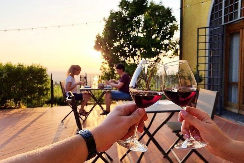Two people toasting with wine glasses, a patio setting, and a sunset in the background. 1