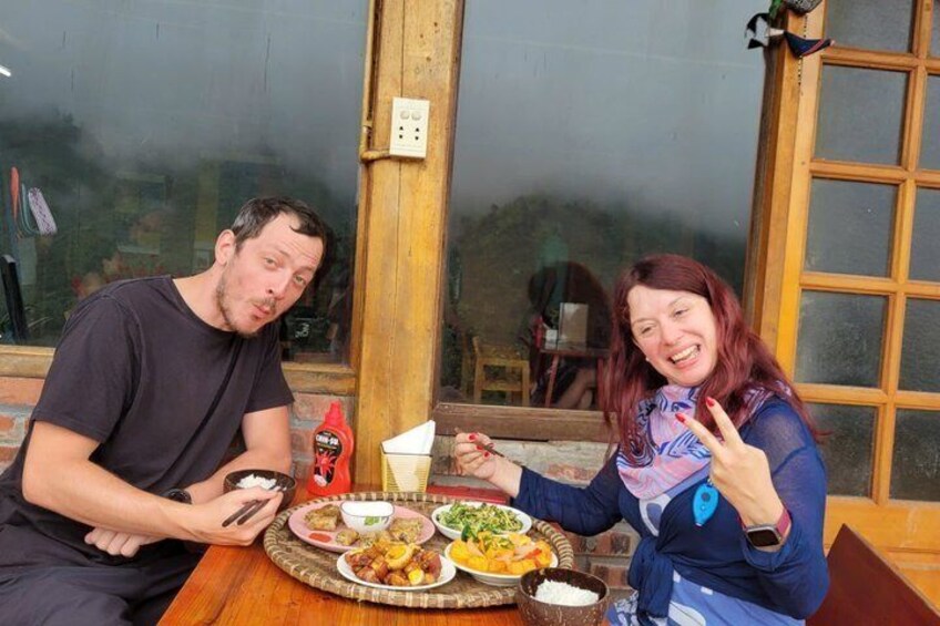 Two people sitting at a table with various dishes, a window, and a door in the background. 3