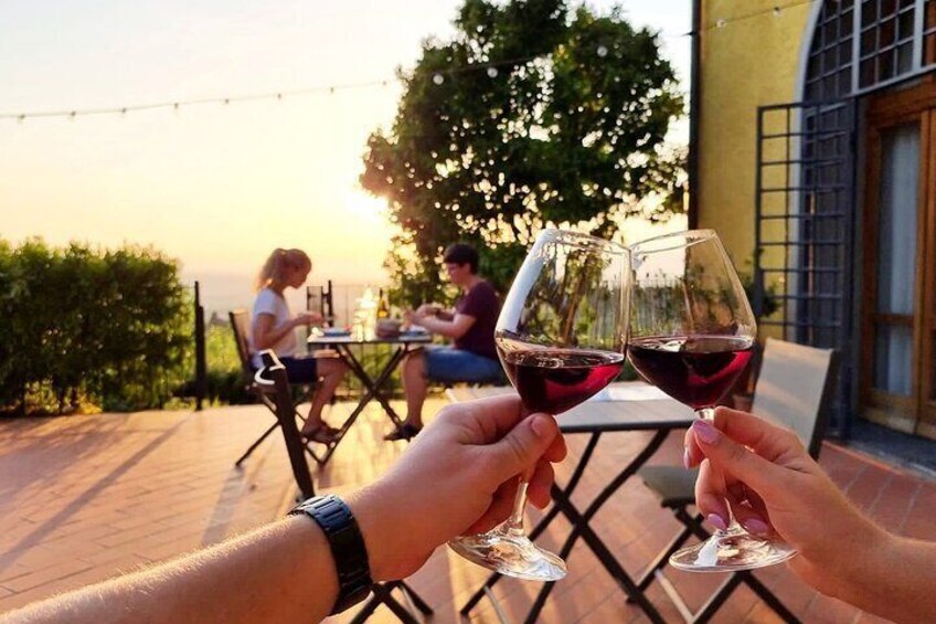 Due persone brindano con bicchieri di vino, un'area patio e un tramonto sullo sfondo. 1